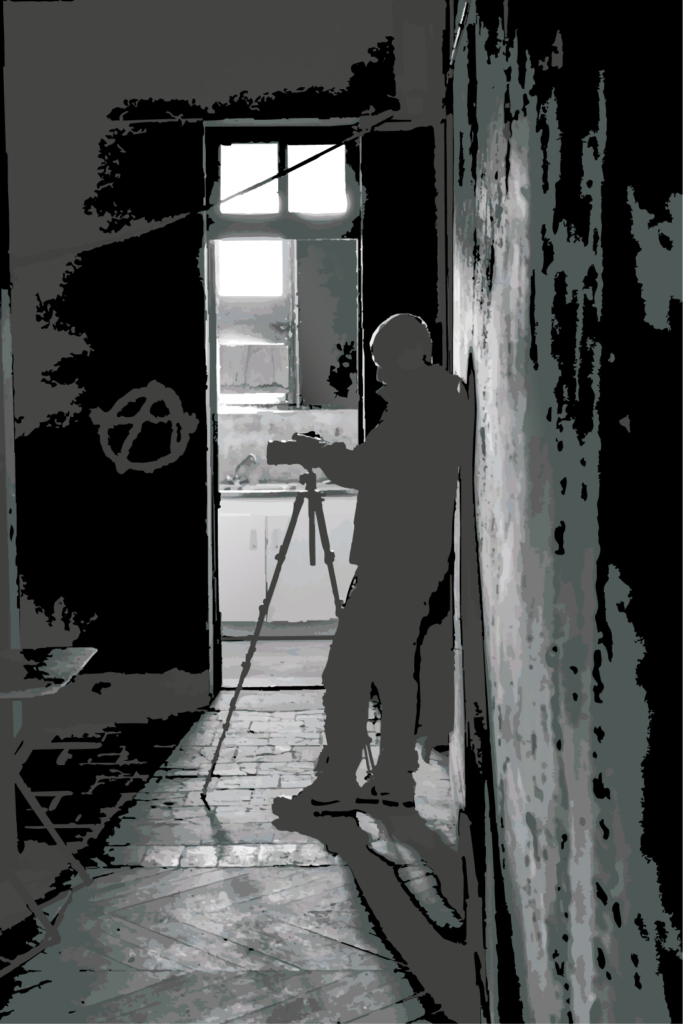 Dans un espace presque entièrement absorbé par l’ombre, une silhouette se tient face à son appareil photographique. La lumière venue de la pièce voisine découpe le corps, le trépied et l’architecture, transformant une scène ordinaire en composition graphique faite de masses, de passages et de tensions.

L’image ne montre pas seulement un photographe au travail : elle met en scène l’acte même de regarder. Celui qui observe devient à son tour une présence observée, réduit à une silhouette, presque anonyme, tandis que l’appareil semble devenir le véritable point de contact entre l’espace visible et ce qui cherche encore à apparaître.

Le traitement volontairement épuré, proche de l’aplat et de la gravure contemporaine, efface une partie des détails pour renforcer les lignes, les contrastes et les matières. Les murs, le sol, l’encadrement de la porte et la lumière construisent une profondeur presque théâtrale, comme si la scène se situait à la frontière entre document et fiction.

Cette œuvre parle ainsi du regard, mais également de la position de celui qui crée : présent dans l’image tout en restant en retrait, entre l’ombre et la lumière, entre ce qui existe déjà et ce qu’il tente de révéler.